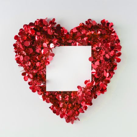 Red confetti shaped in heart around paper card