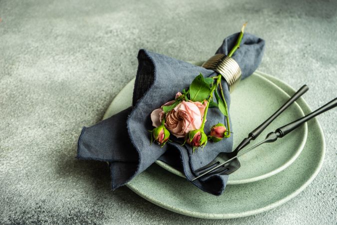 Flowers wrapped with navy napkin on grey plate and concrete background