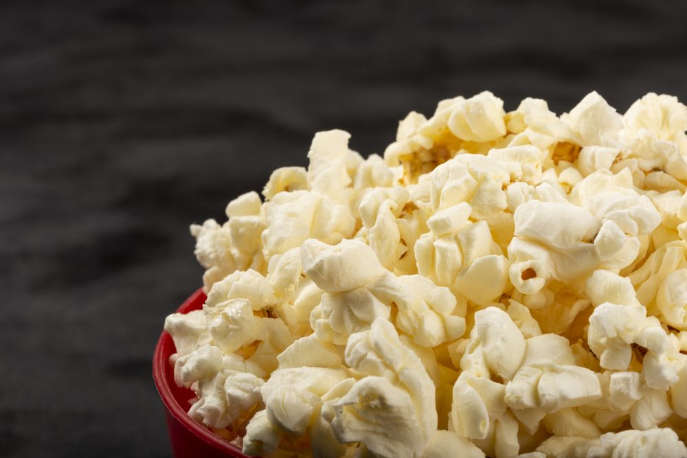 Bowl with salted popcorn sore the table.