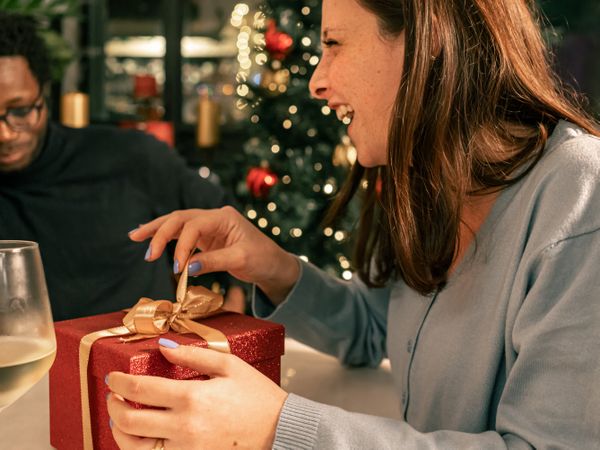 Happy woman laughing with joy while opening a gift at a Christmas party