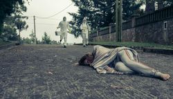 People in bacteriological protective suits running to help a woman