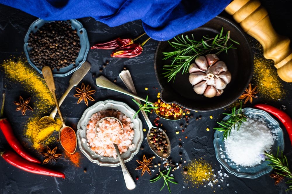 Spices and herbs in teal bowls on counter