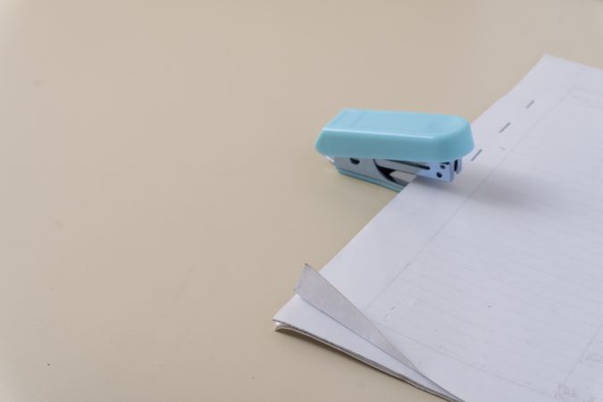 A stapler in action clipping a stack of paper