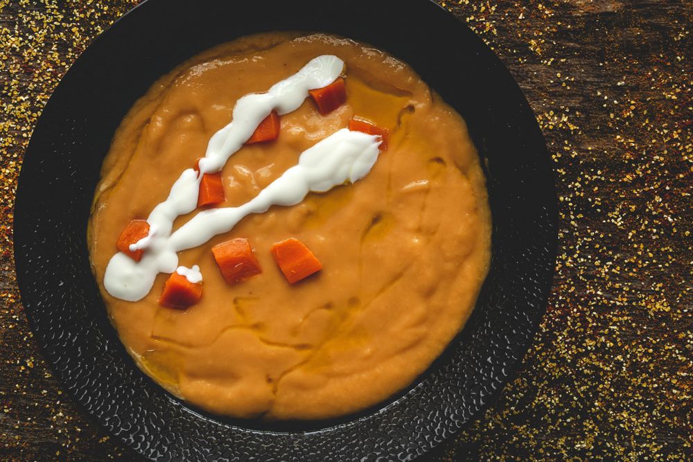 Orange cream soup and sliced carrot in bowl