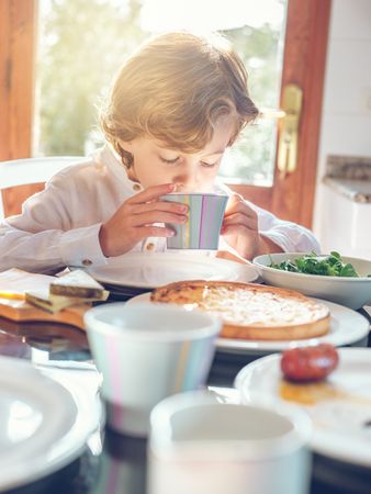 Little boy drinking beverage in morning at home