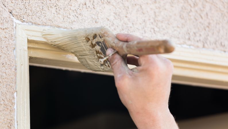 Professional Painter Cutting In With Brush to Paint House Door Frame.