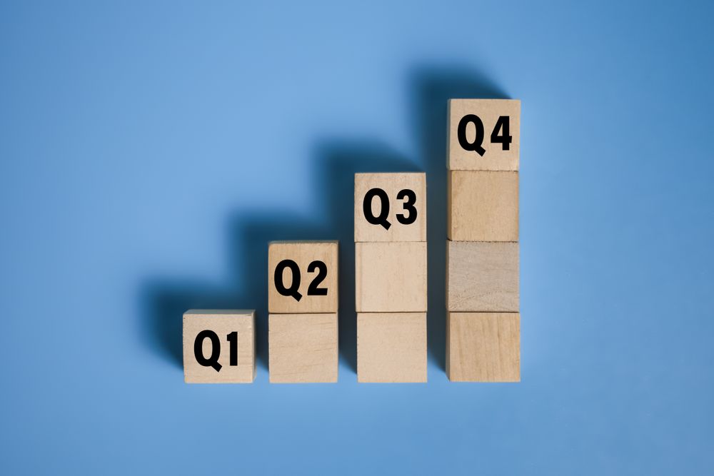 wooden cubes with q1, q2, q3, q4 symbol isolated on blue background. concept of quarterly report annual