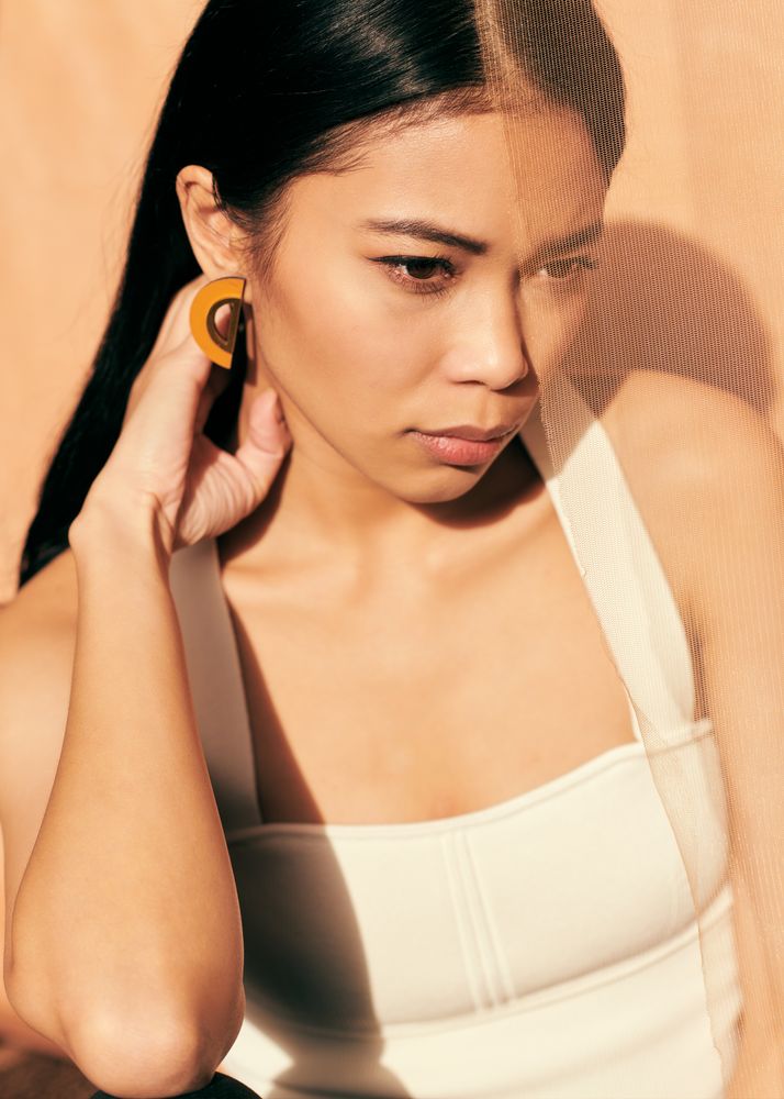 Young woman looking down and resting her hand on her neck