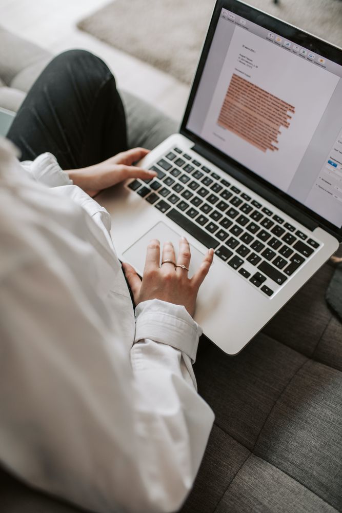 Back view of woman using laptop sitting on a couch