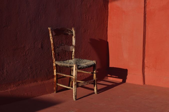 Old wooden one vintage chair in a room with red grunge walls