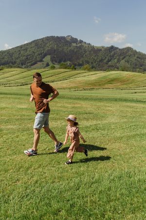 Happy father and daughter running in countryside