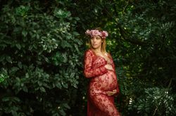 Pregnant woman with closed eyes touching belly and chin while standing in garden in sunny day