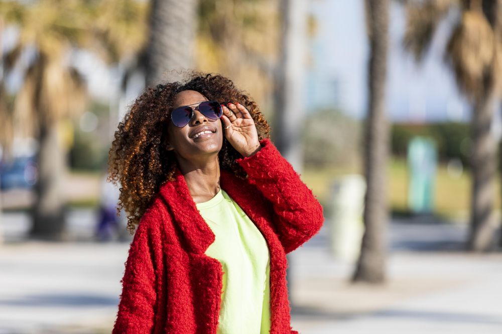 Female with head to the sun on street with palm trees