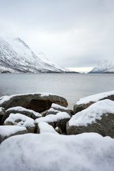 Scenic view from sea stones on snowy mountains