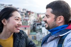 Positive multiethnic resting couple talking while walking at city street