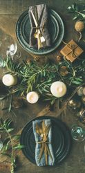 Festival holiday table setting on wooden table, with gold ornaments and branches, narrow composition