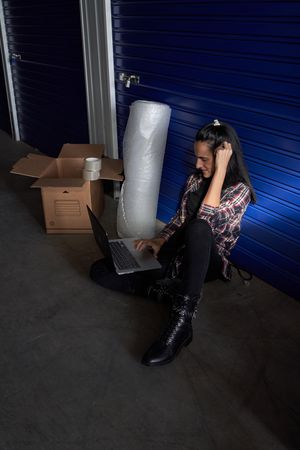 Woman browsing laptop at storage near box