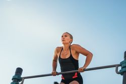 Woman doing dips on a bar outdoors, calisthenics