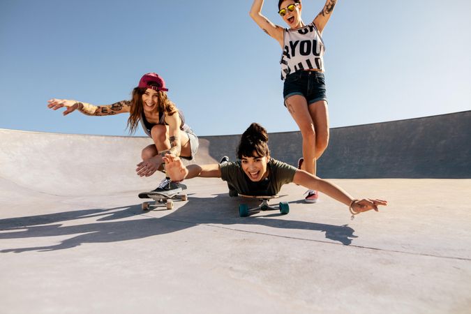 Group of women being silly while riding skateboards at skate park