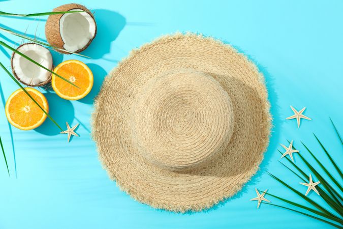 Straw hat, oranges, coconuts, palm leaves and starfishes on color background, space for text and top view. Summer vacation backdrop