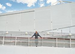 Stylish young man leaning on fence on ramp
