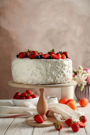 Composition with delicious berry cream cake on wooden table. Tasty dessert