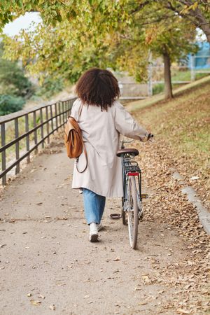 Woman with bicycle walking in park during autumn