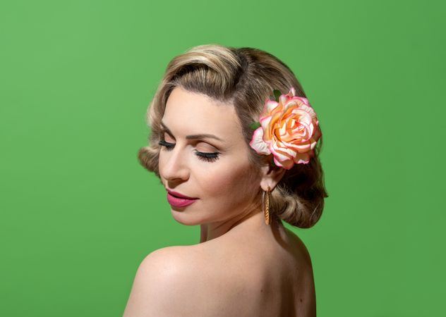 Pin up woman portrait with retro hairstyle and make up, against a green background