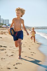 Innocent lovely children running on sandy beach in swimsuits