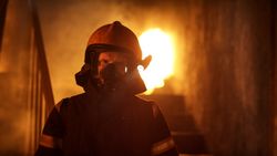 Portrait of a fireman standing in front of a burning building
