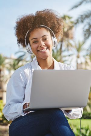 Smiling Black woman with laptop on street