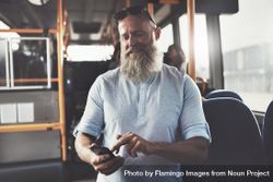Man with gray beard smiling while texting on public transport 4m71N0