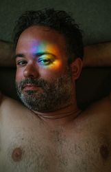 Bearded man with rainbow glare on face