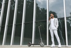 Elegant Black man talking smartphone leaning building
