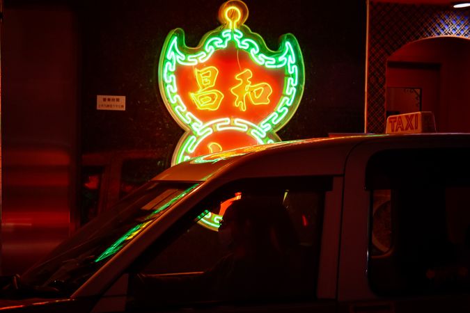 Taxi cab beside lit signage at night in Hong Kong