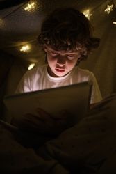 Calm boy drawing in dark blanker fort
