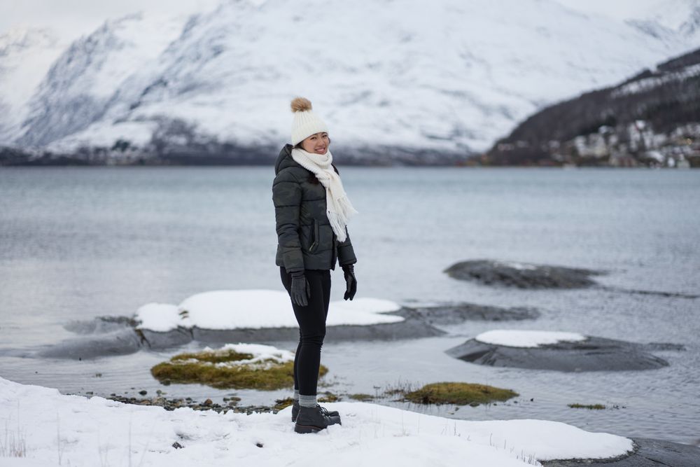 Young asian woman on pond shore against highland in winter