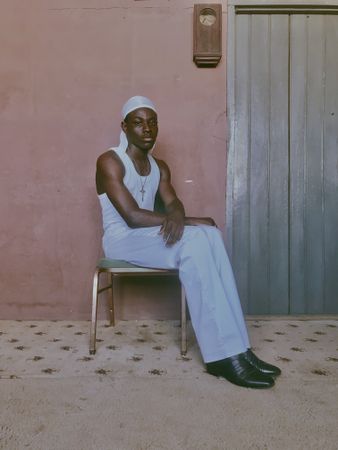 Young man in light tank top sitting on chair indoor