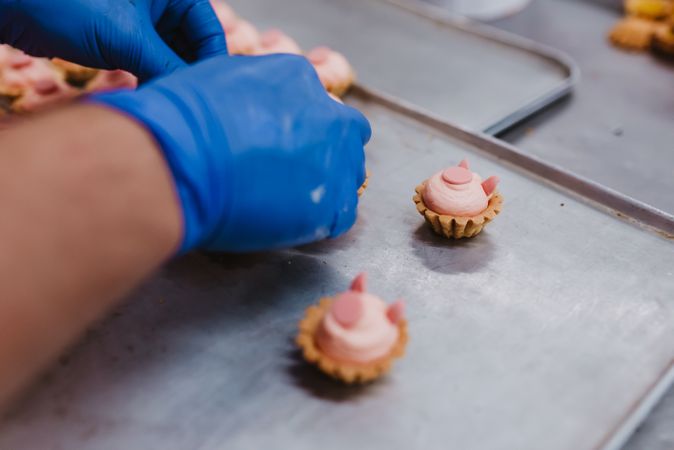 Anonymous baker decorating small cakes