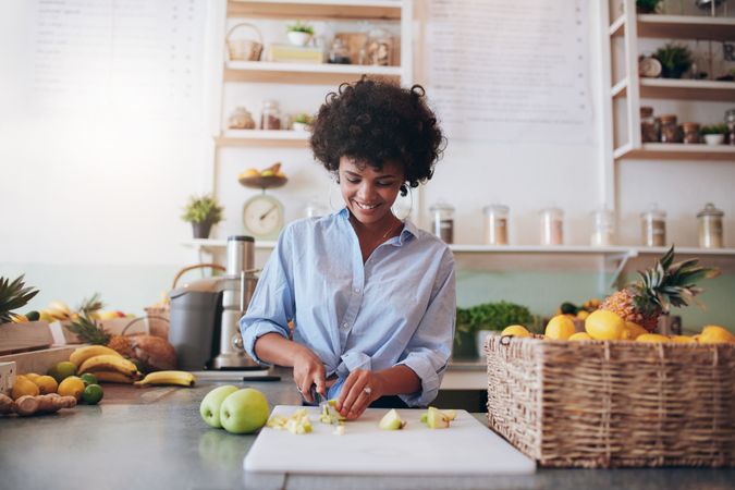 Attractive young woman chopping fruit to make a fresh juice