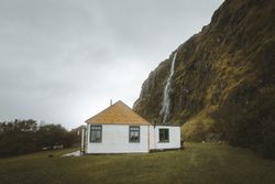 Rural house at foot of huge mossy cliff