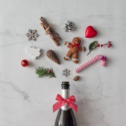Champagne bottle with festive decorations; ribbons, candy cane, gingerbread, on marble background