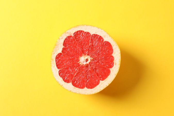 Grapefruit slice on yellow background, space for text