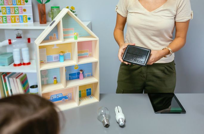 Teacher in ecology classroom showing a solar panel next to incandescent light bulb and led lamp