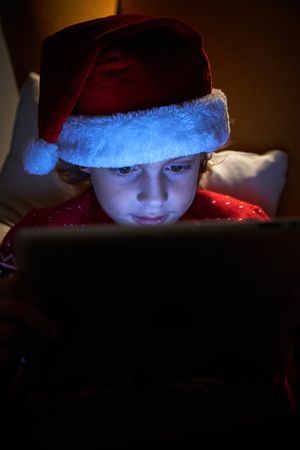 Kid in Christmas hat with tablet