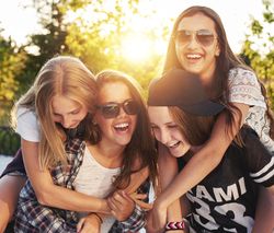 Group of female teenagers having fun with piggy backs in the sun