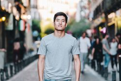 Confident Asian man walking along city street