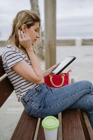 Woman sitting on bench and using tablet