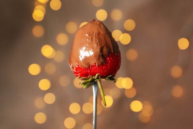 Chocolate fondue. Strawberry in chocolate against brown background with blurred lights
