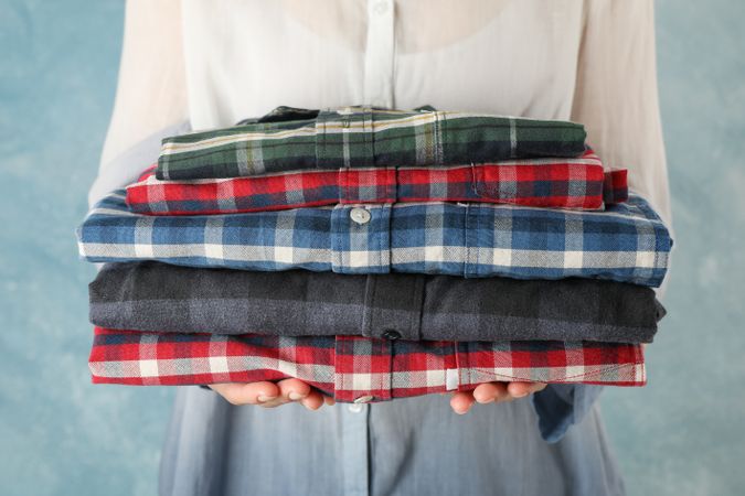 Female person hold folded shirts, close up